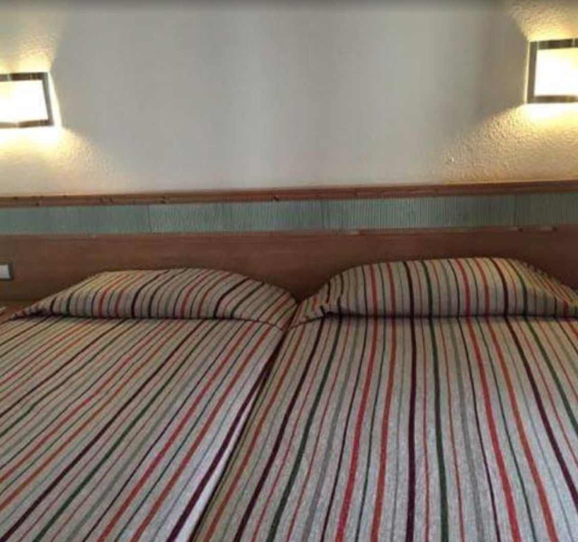 Ein Hotelzimmer mit zwei Betten und zwei Lampen an der Wand.