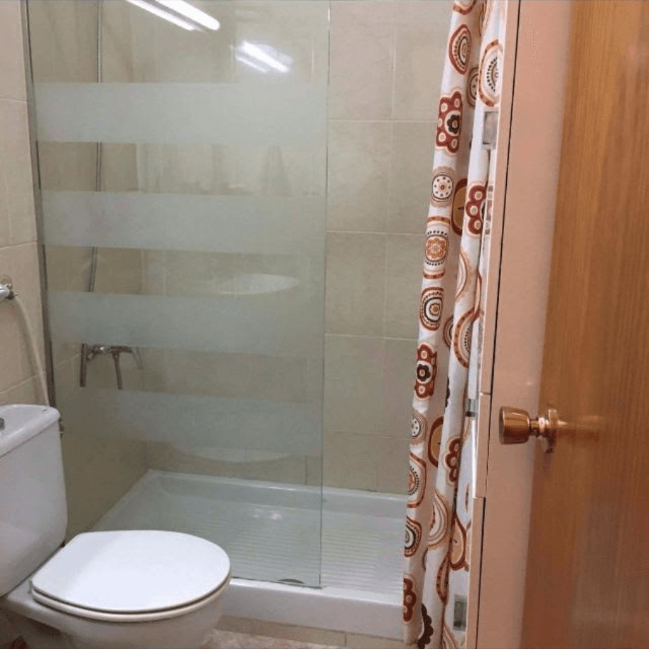 Ein Badezimmer mit Toilette, Dusche und Duschvorhang