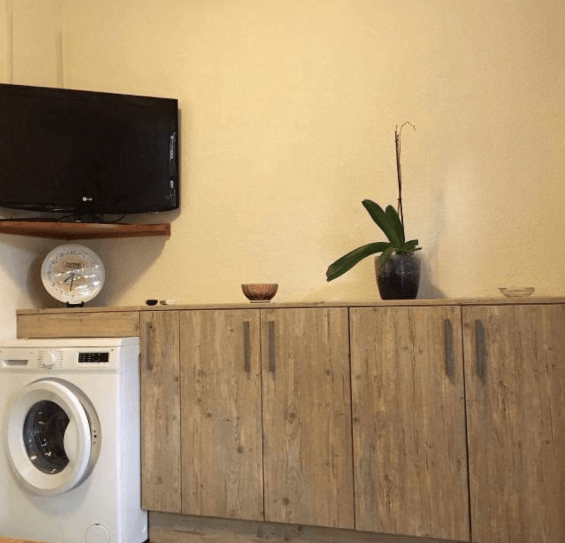 Eine Waschküche mit Waschmaschine und Trockner sowie einem Flachbildfernseher