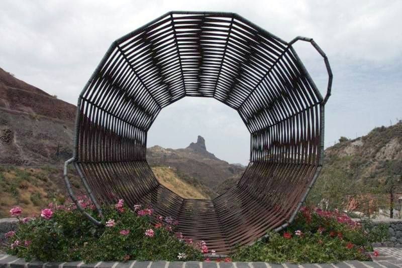 Eine große Metallskulptur mit Blumen davor