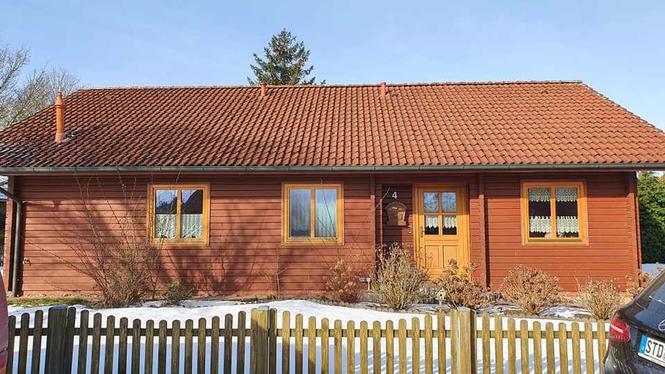 Ein Haus mit einem Holzzaun und einem davor geparkten Auto.