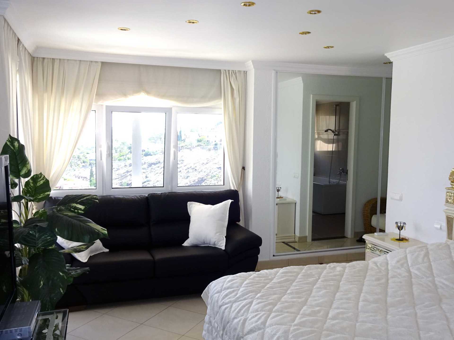 Ein Schlafzimmer mit einer schwarzen Couch und einem weißen Bett