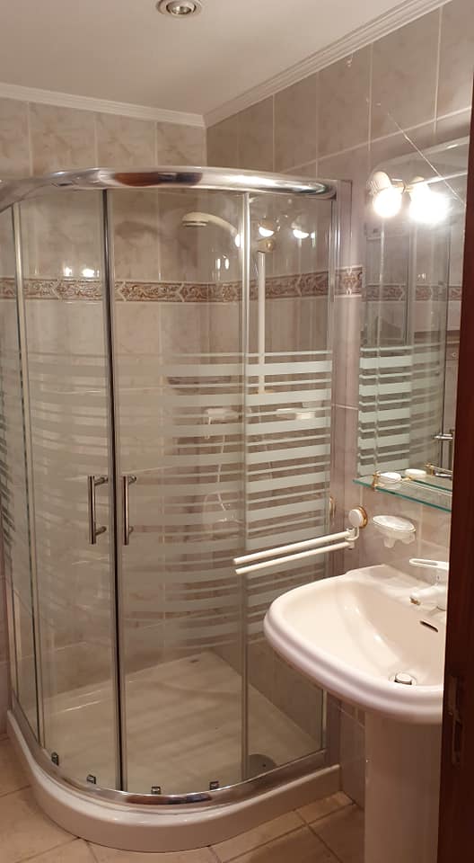 Ein Badezimmer mit Dusche, Waschbecken und Spiegel.