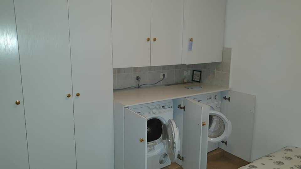 Eine Waschmaschine und ein Trockner sind in einem Schrank in einer Waschküche eingebaut.
