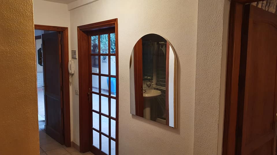 Ein Flur mit einer Tür und einem Spiegel an der Wand