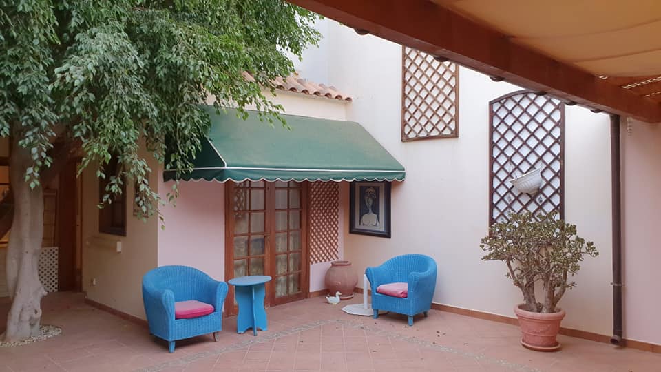 Eine Terrasse mit blauen Stühlen und einer grünen Markise
