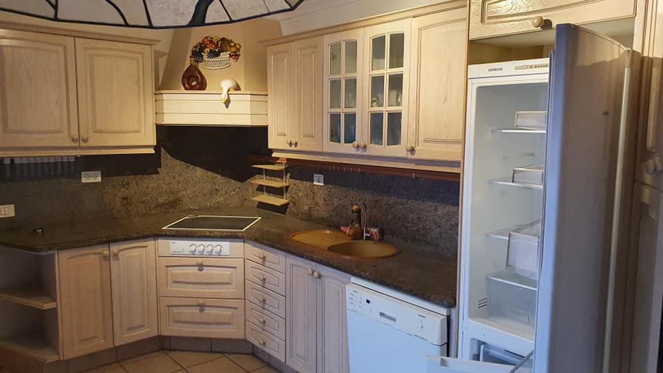 Eine Küche mit weißen Schränken, einem Kühlschrank, einer Spüle und einer Spülmaschine.