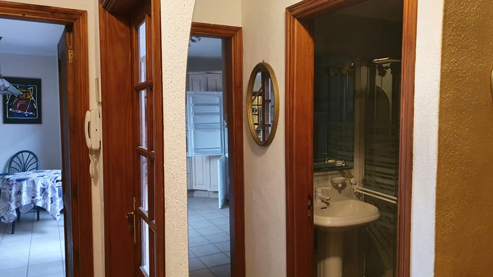 Ein Flur mit einem Waschbecken und einem Spiegel an der Wand.
