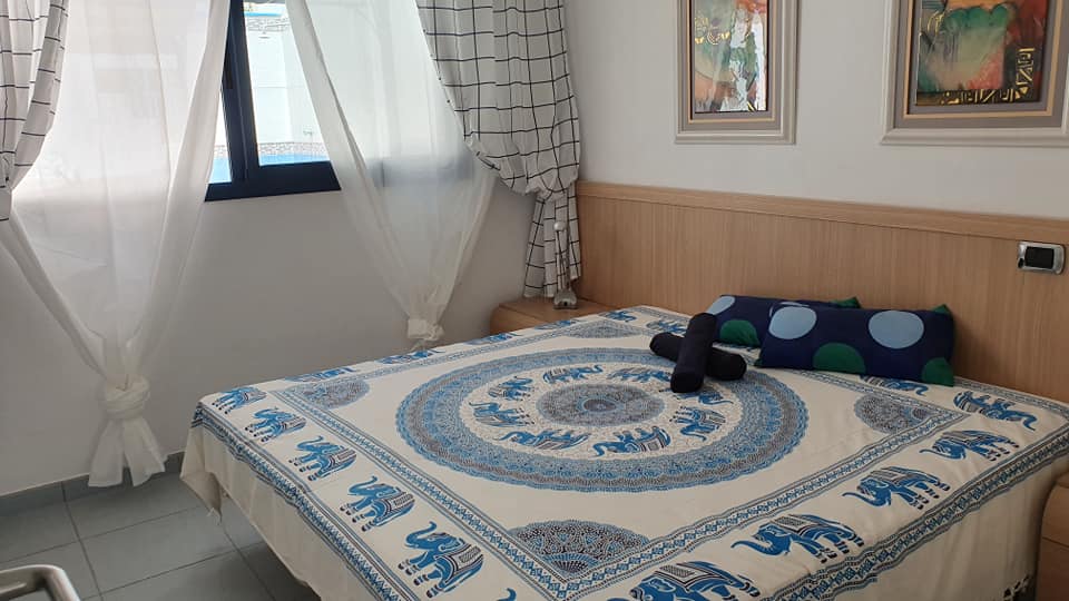 Ein Bett mit einer blau-weißen Decke darauf in einem Schlafzimmer.