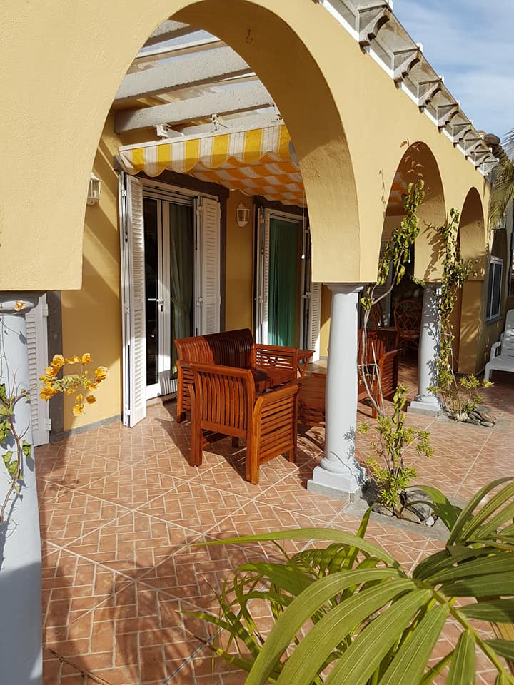 Eine Terrasse mit Sofa und Stühlen unter einem Baldachin