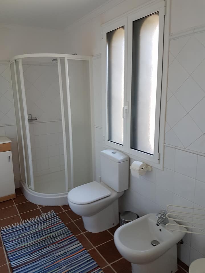 Ein Badezimmer mit Toilette, Bidet, Dusche und Fenster.