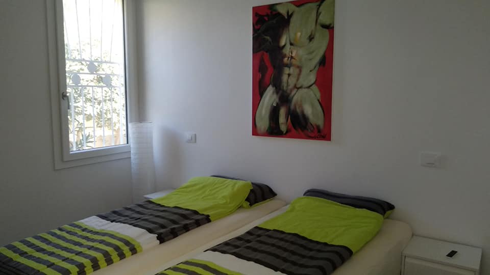 Ein Schlafzimmer mit zwei Betten und einem Gemälde an der Wand darüber.