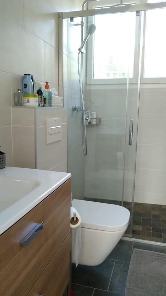 Ein Badezimmer mit Toilette, Waschbecken, Dusche und Fenster.