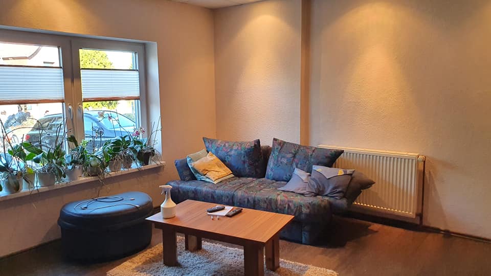 Ein Wohnzimmer mit Couch, Couchtisch, Ottomane und Fenster.