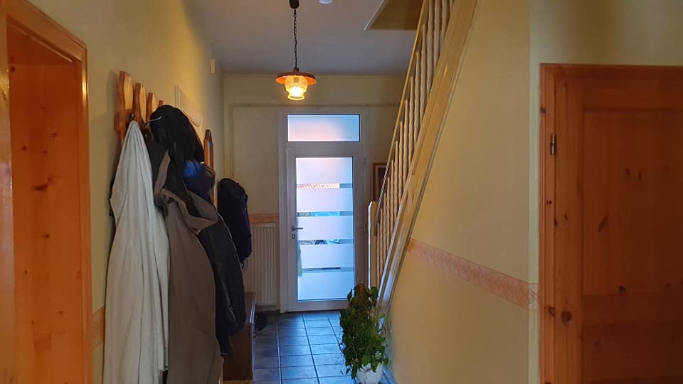 Ein Flur mit an Haken hängenden Mänteln und eine Treppe.