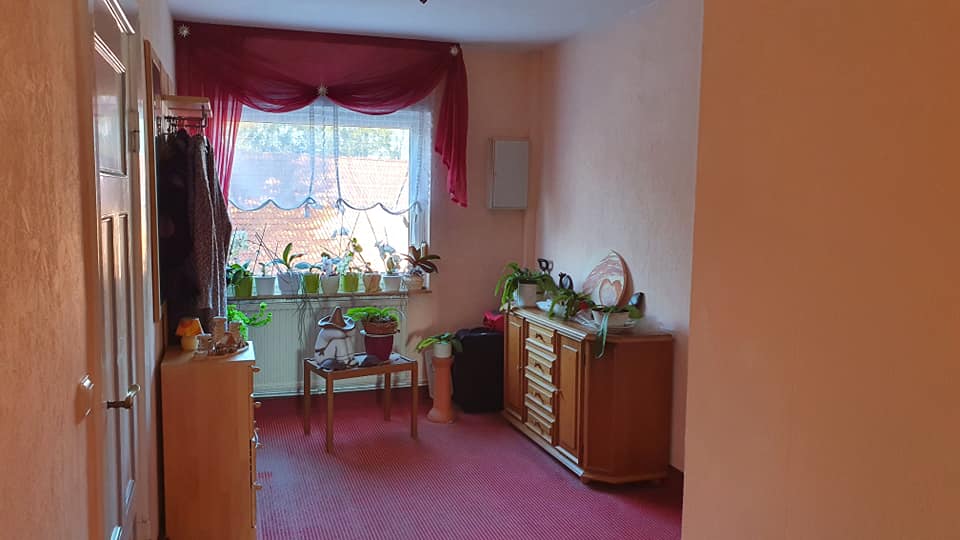 Ein Wohnzimmer mit einer Kommode, Stühlen und einem Fenster.
