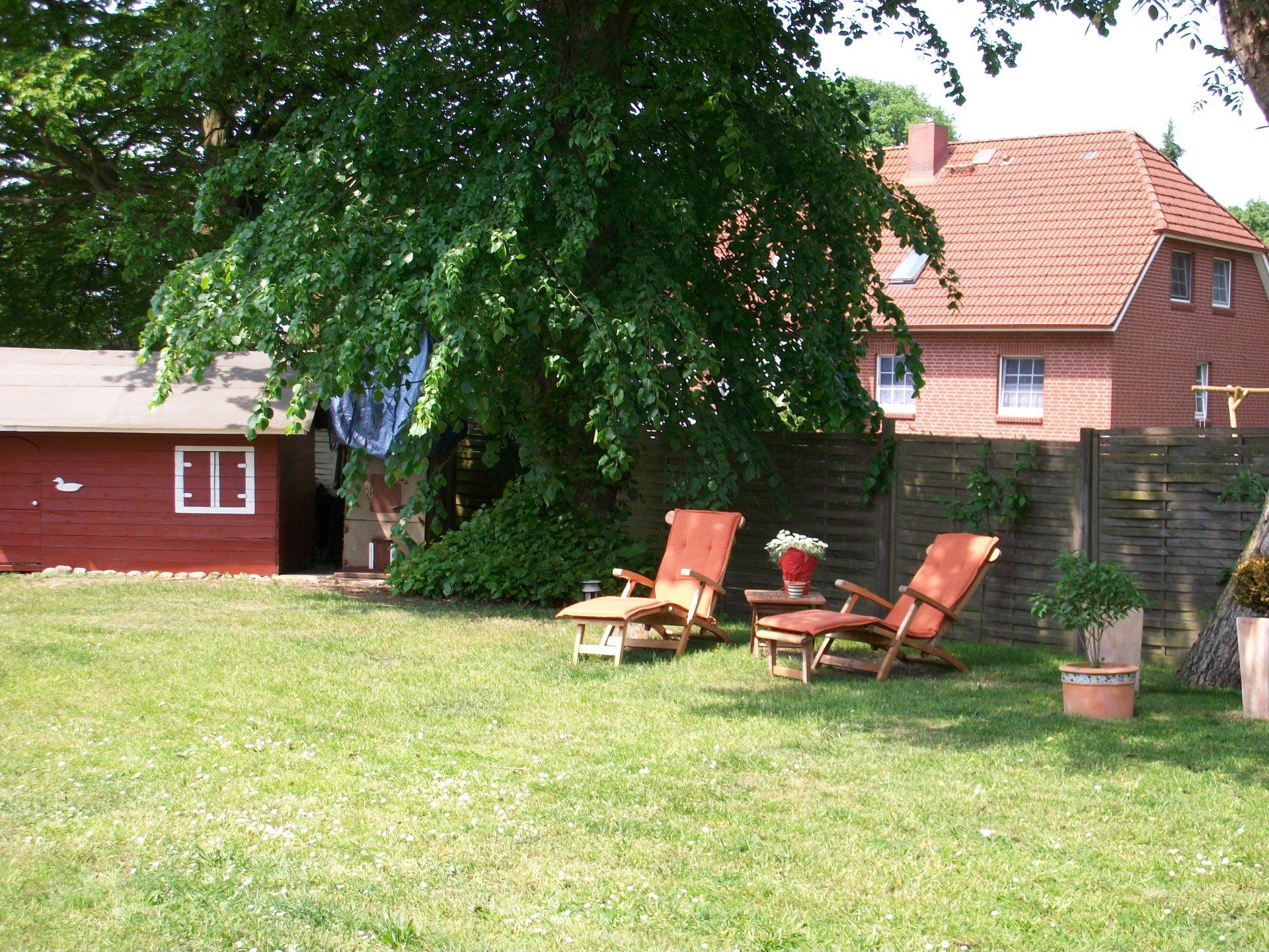 Ein Hinterhof mit Gartenstühlen und einem roten Haus im Hintergrund