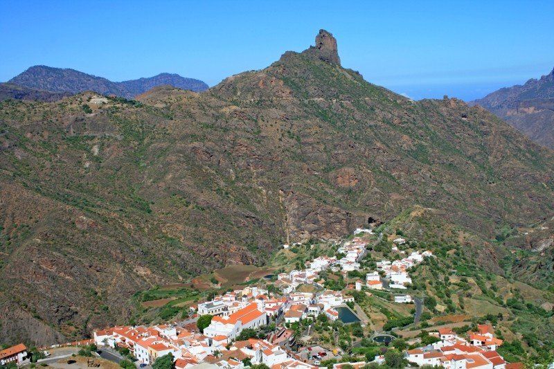 Ein kleines Dorf ist von Bergen und Bäumen umgeben