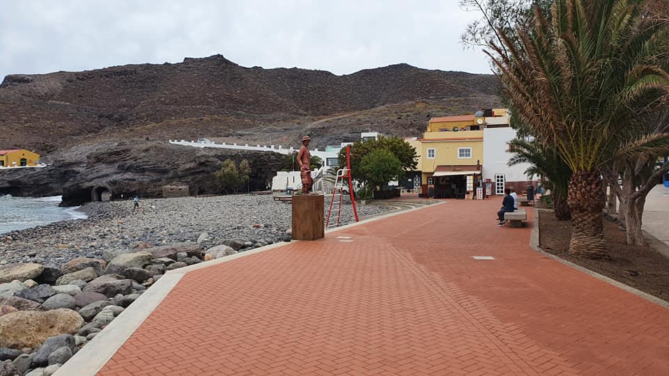 Ein Ziegelweg führt zu einem Strand, im Hintergrund ist ein Gebäude zu sehen.