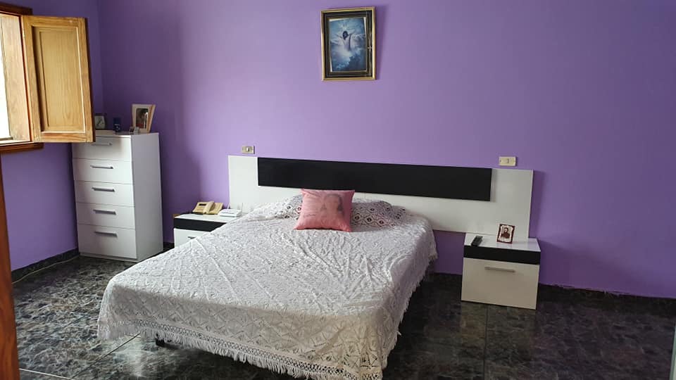 Ein Schlafzimmer mit lila Wänden und einem weißen Bett