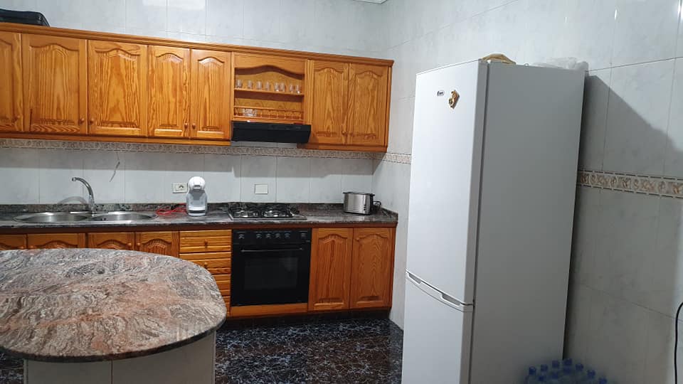 Eine Küche mit Holzschränken und einem weißen Kühlschrank.