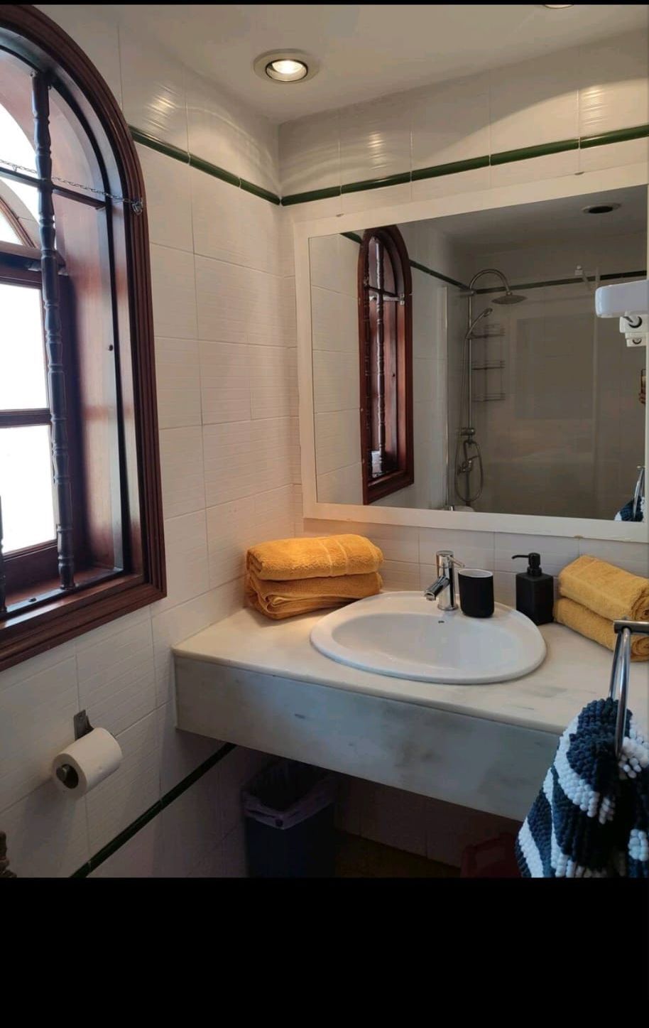 Ein Badezimmer mit Waschbecken, Spiegel, Handtüchern und Fenster.