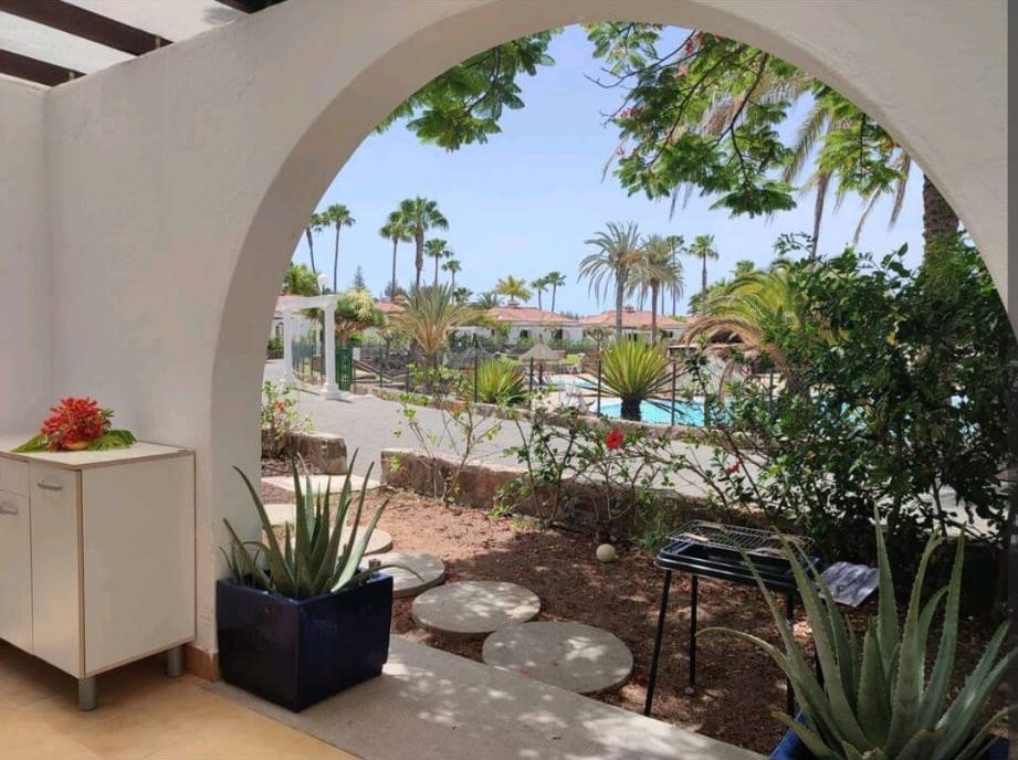 Eine Terrasse mit Blick auf einen Pool und Palmen