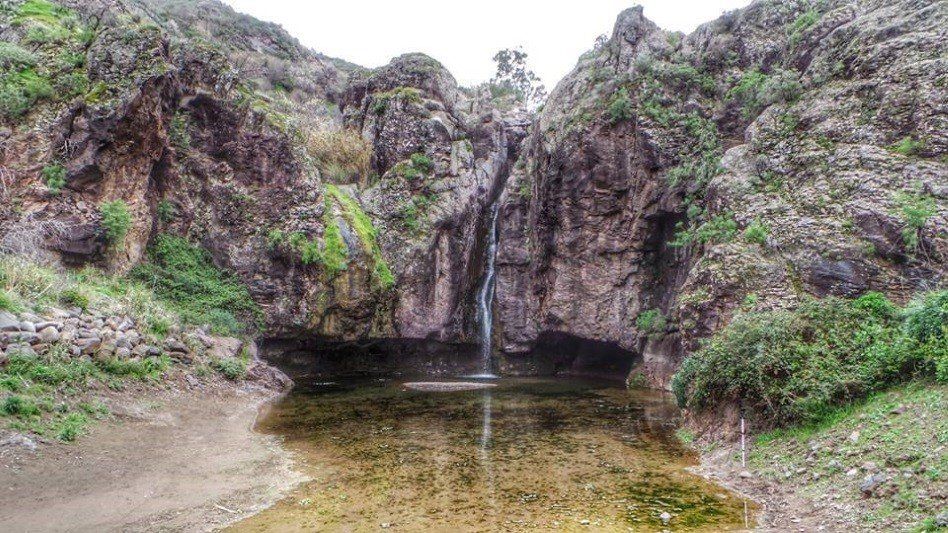 Ein Wasserfall ist von Felsen und einem kleinen Teich umgeben.