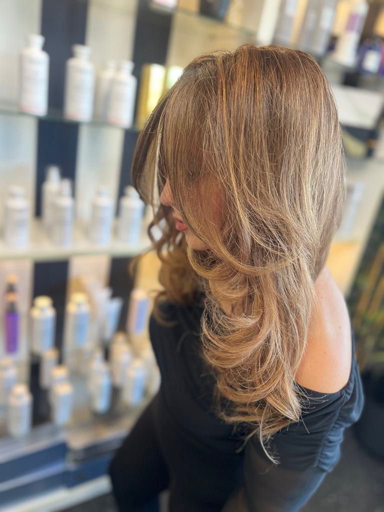 A Woman With Long Brown Hair is Sitting in a Salon — Xquisite Styles in Mount Warrigal, NSW