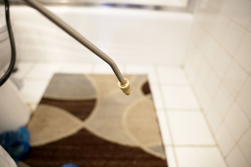 Spray nozzle pointed toward a bathroom floor with a rug.