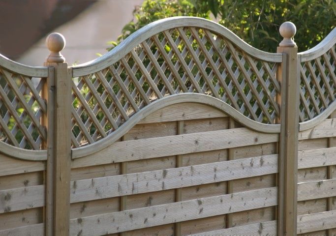 Wooden fence with lattice top, tan color, in a garden.