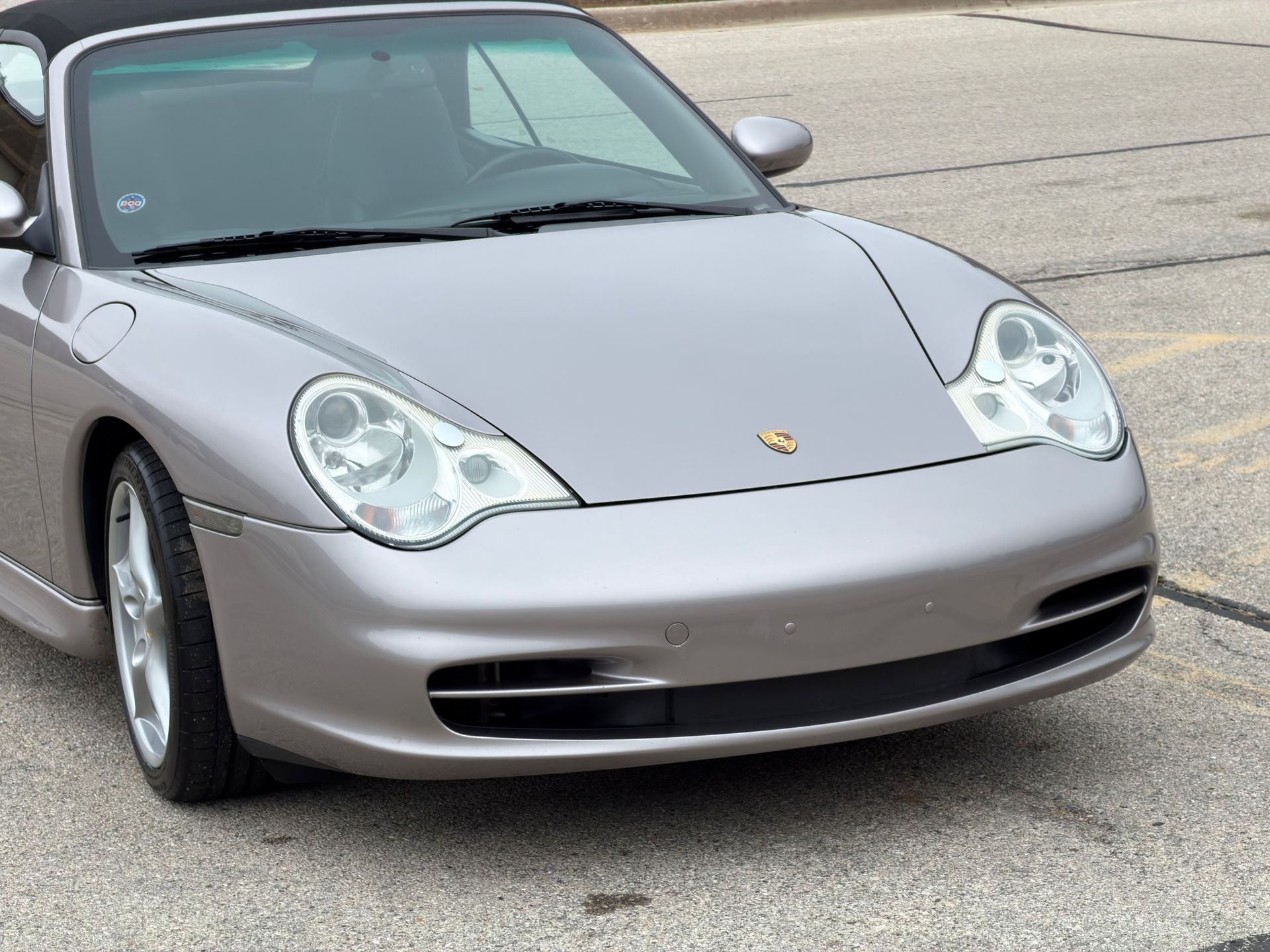 Silver Porsche convertible car on pavement.