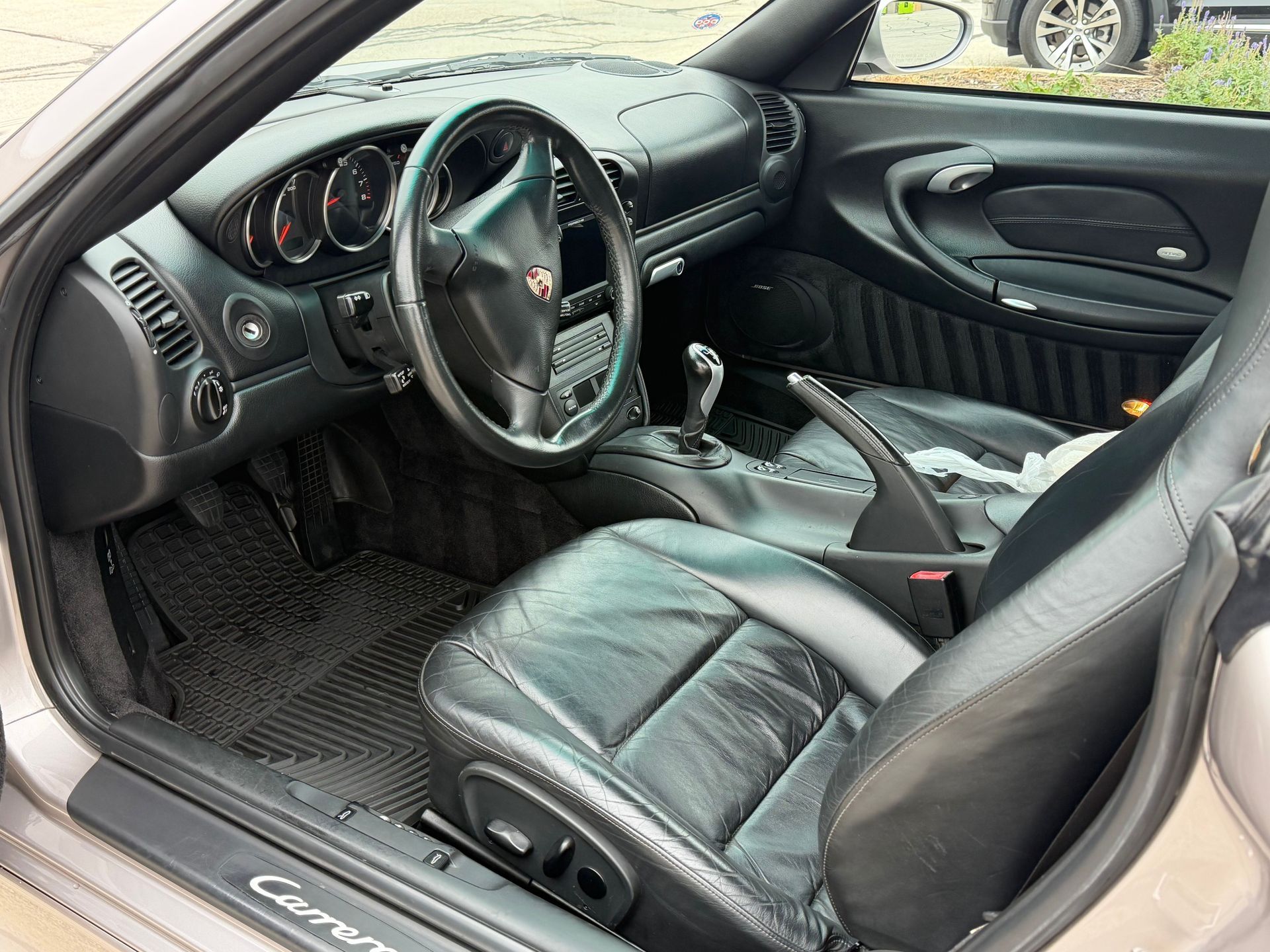 Interior view of a gray Porsche Carrera with black leather seats, dashboard, and a manual gear shift.