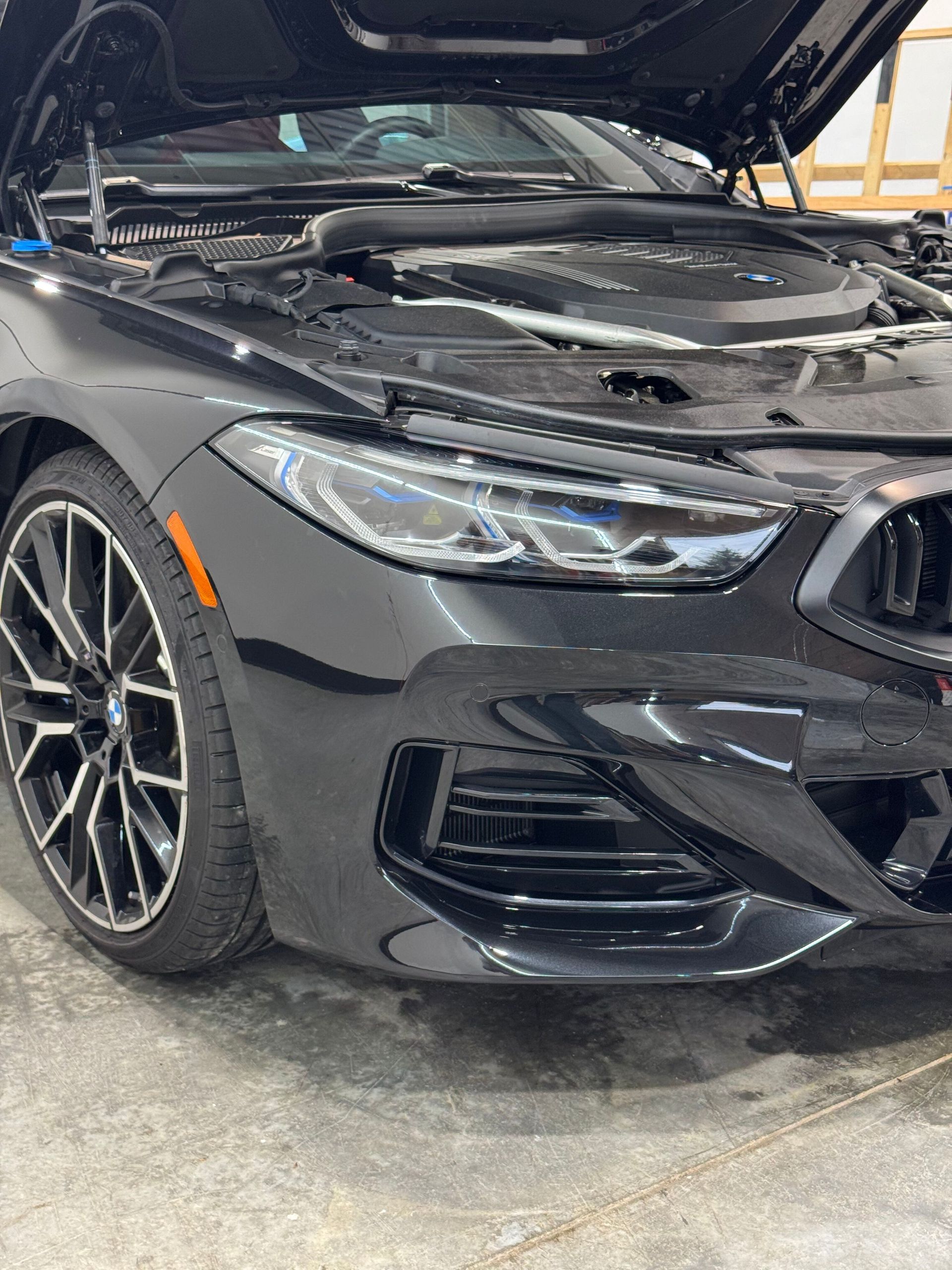 Black Nissan Z sports car parked on a street under a bright, sunny sky.