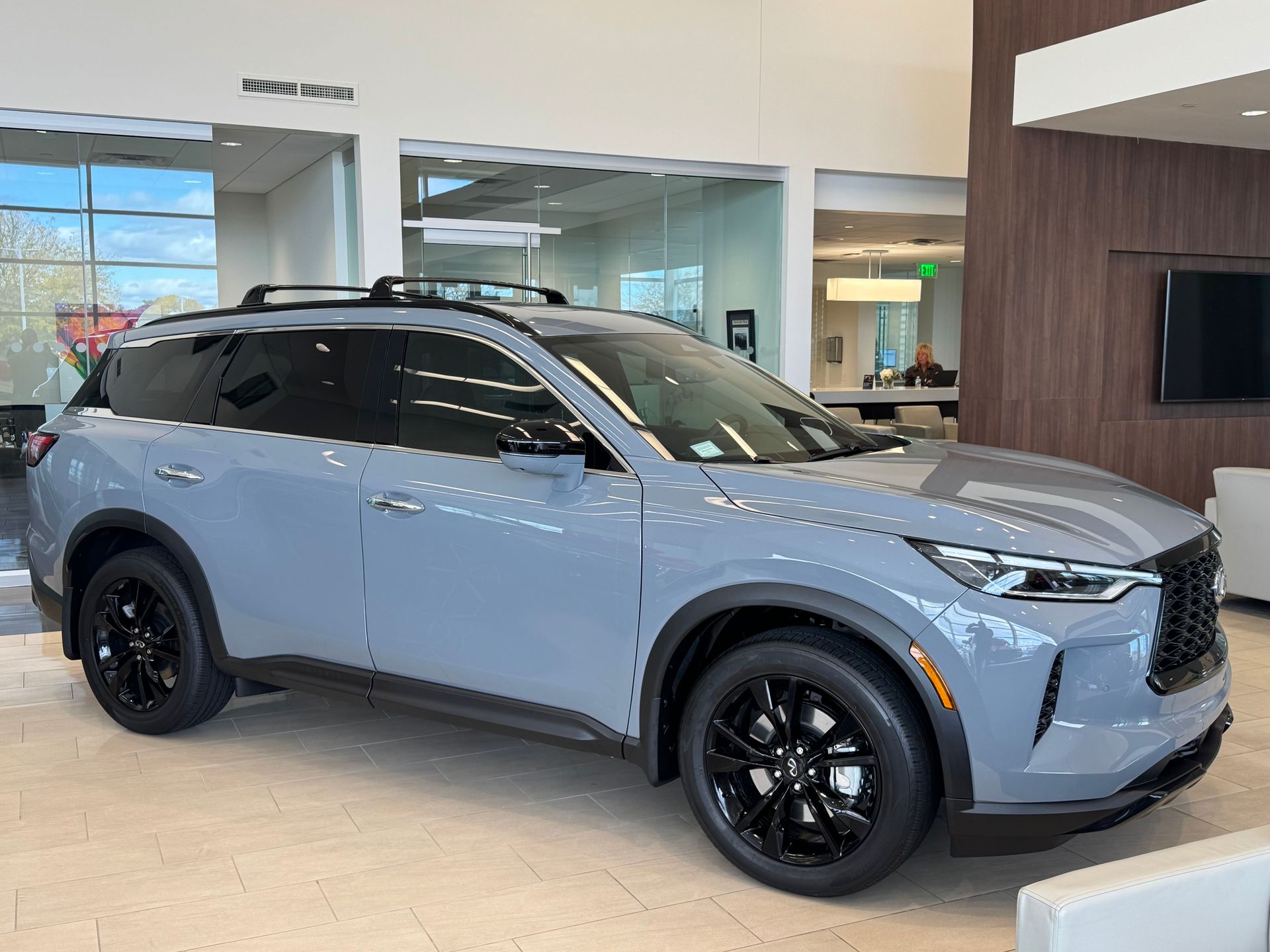 Gray SUV with black wheels and roof rack, indoors, showroom.