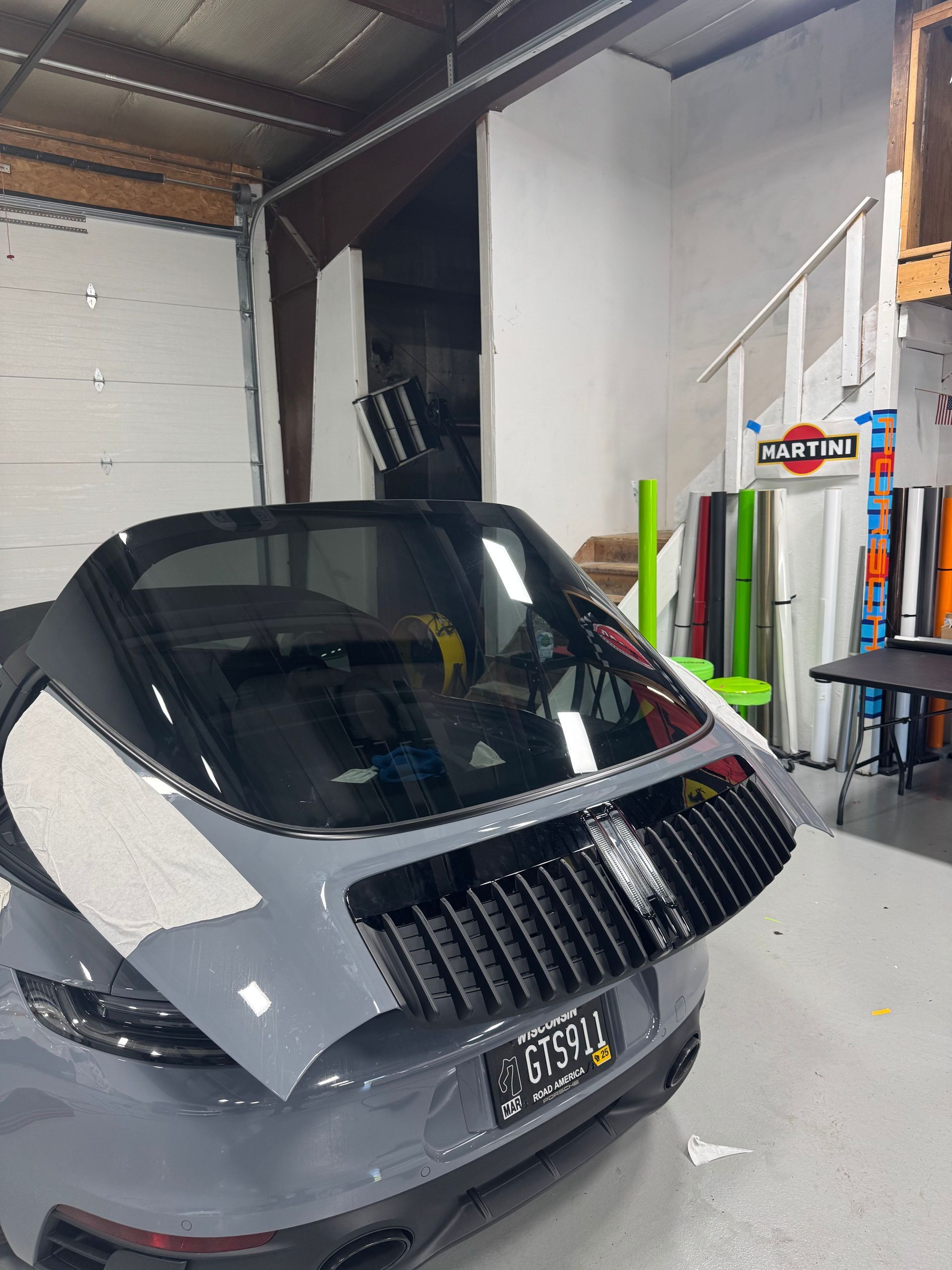 Gray Porsche with its rear lid open in a garage, showcasing the engine bay.