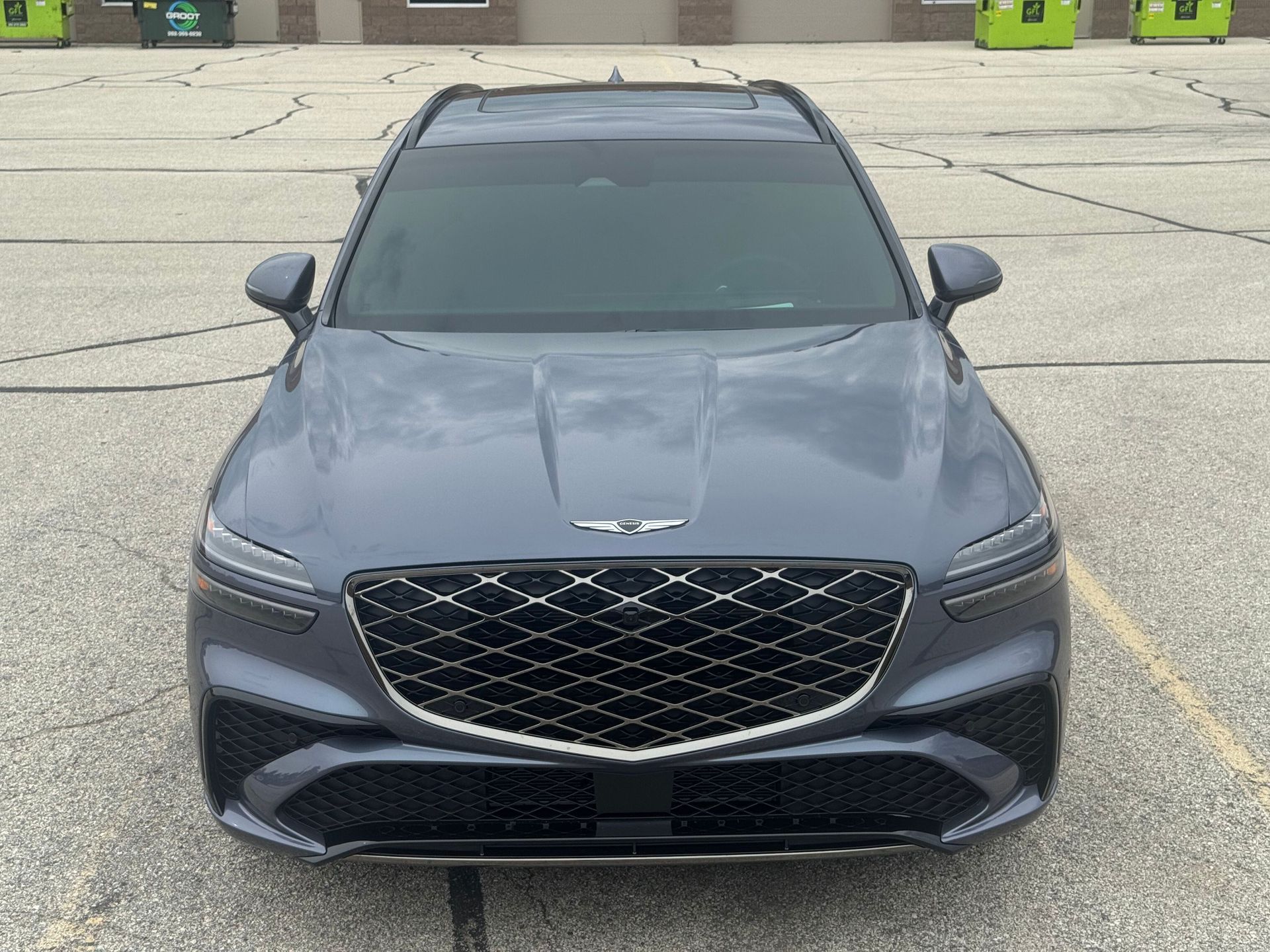 Gray Genesis GV70 SUV with a large front grille, parked outside.