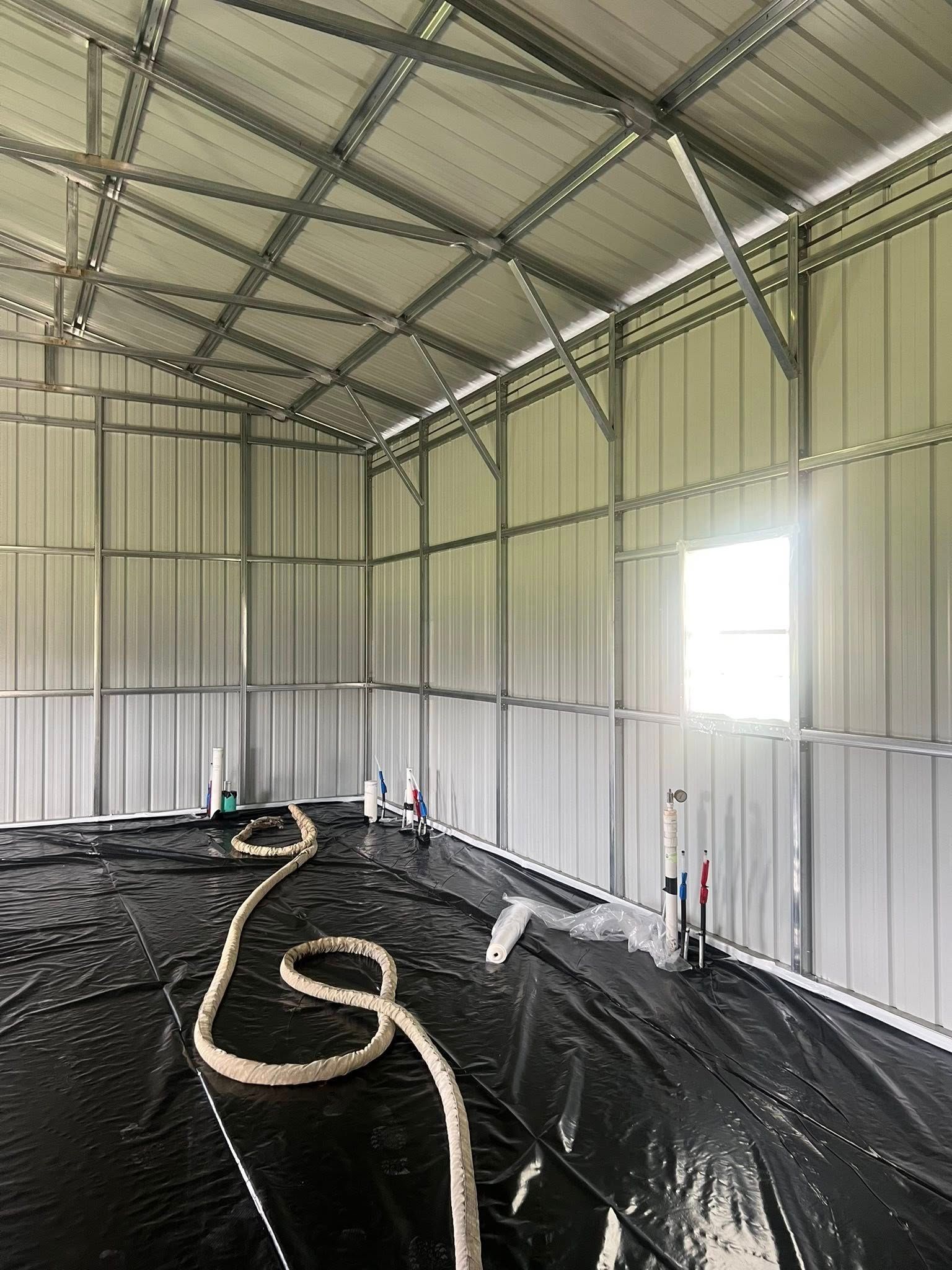 A large metal building with a hose in the middle of it.