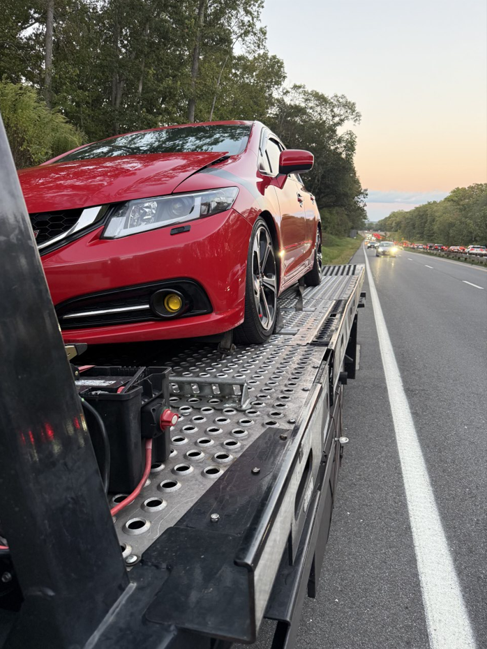 Car loaded on flatbed on busy highway