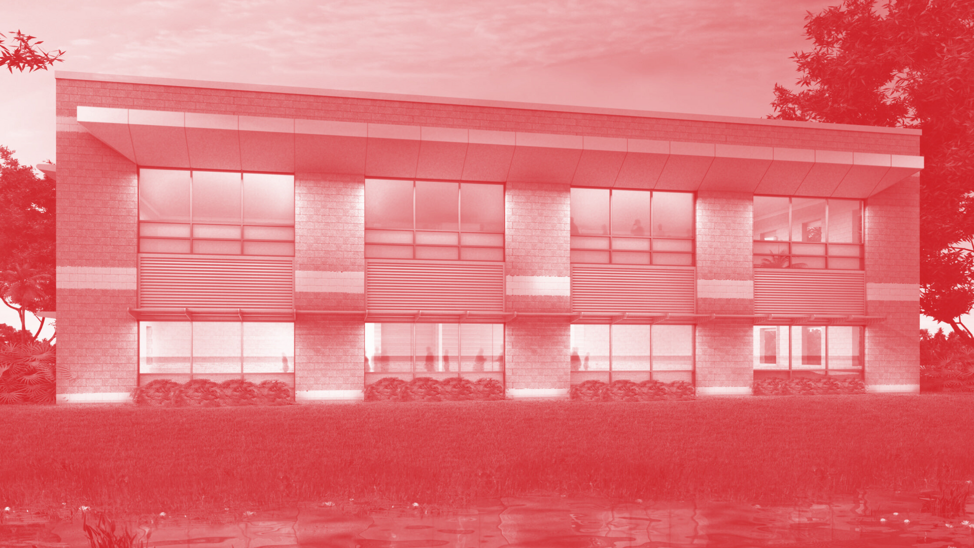 A large building with a lot of windows sits next to a body of water