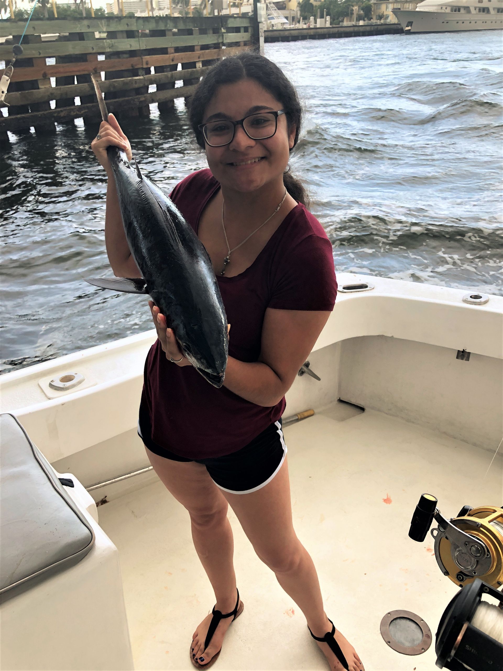 A woman is holding a large fish on a boat.