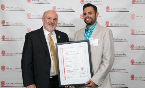 Two men are standing next to each other holding a framed certificate.