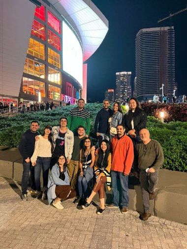A group of people are posing for a picture in front of a building at night.