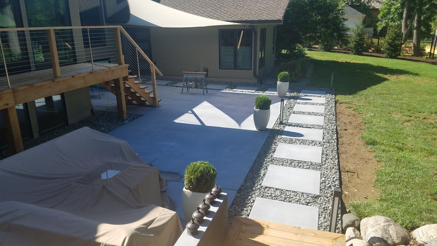 Construction workers in high-visibility orange uniforms pouring wet concrete over a steel rebar grid on a sunny day.