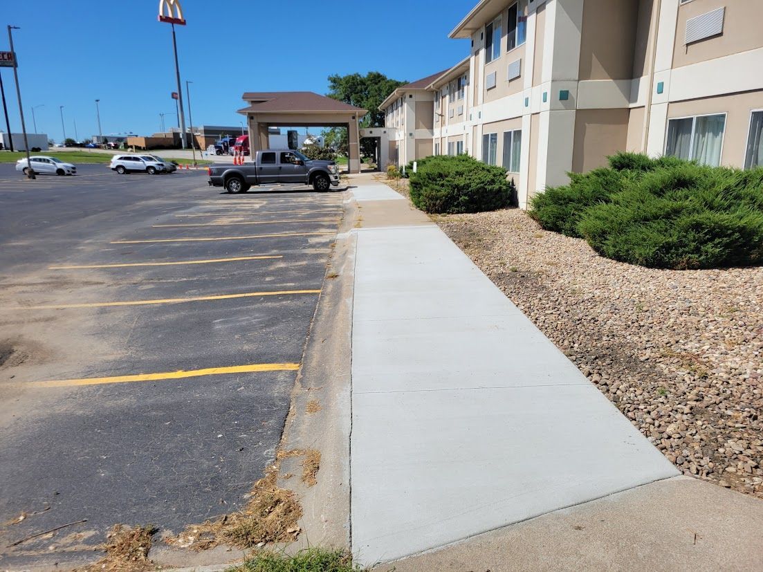 Construction workers use a chute and a rake to pour and spread wet concrete over a prepared gravel surface.