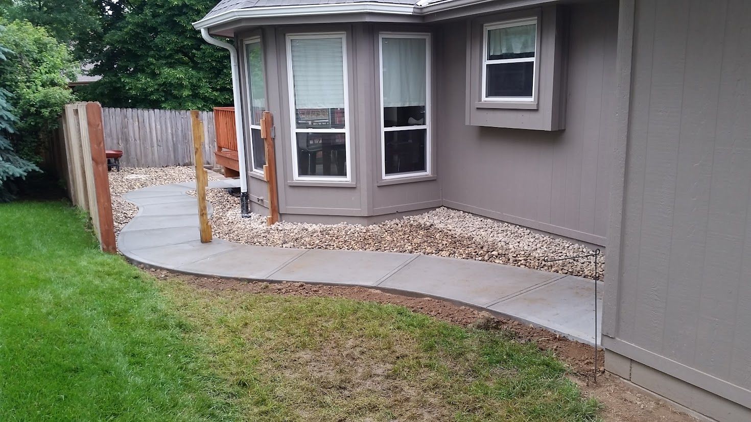 Construction workers in high-visibility vests pour concrete on a site using a hose pump over a reinforced steel grid.