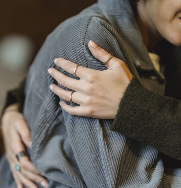 A woman with a ring on her finger is hugging another woman