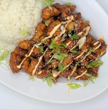 A white plate topped with chicken and rice on a table