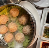 A steamer filled with dumplings and lettuce on a table