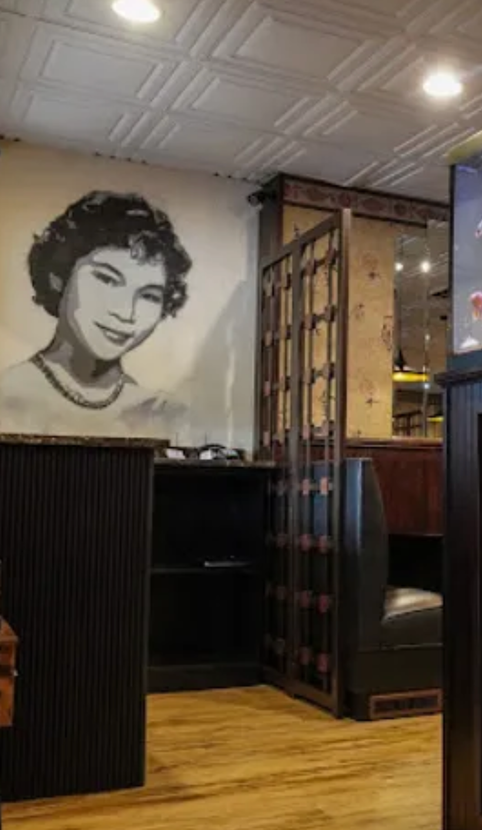 A restaurant with a painting of a woman on the wall.